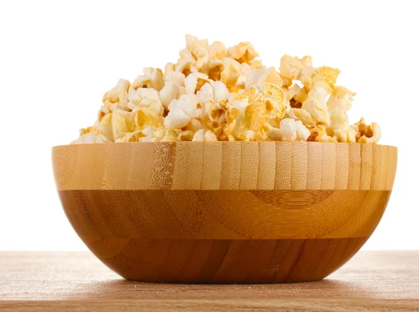 Popcorn in houten kom op houten tafel op witte achtergrond — Stockfoto