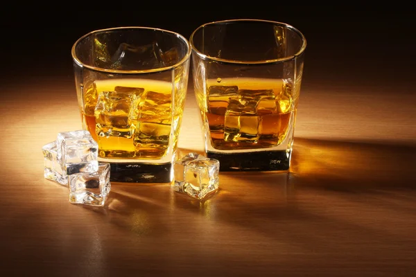 Twee glazen van scotch whisky en ijs op houten tafel — Stockfoto
