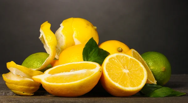 成熟的柠檬和酸橙与灰色的背景上的木桌上的叶子 — 图库照片