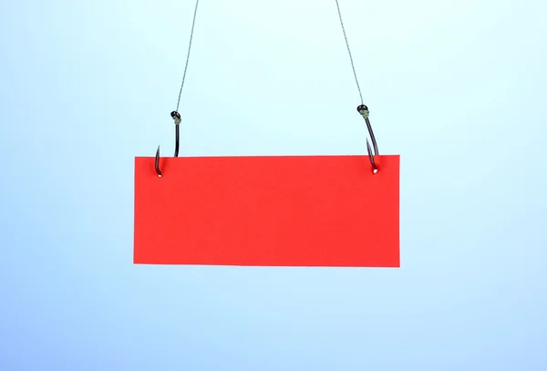 Empty sheet of a paper on fish hooks on blue background — Stock Photo, Image