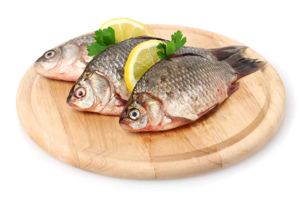 Свежие рыбы с лимоном и петрушкой на деревянной разделочной доске изолированы на белом — стоковое фото