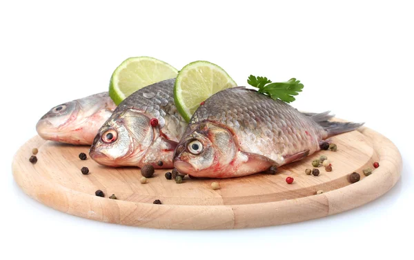 Peixes frescos com limão, salsa e especiarias em tábua de corte de madeira isolada a branco — Fotografia de Stock