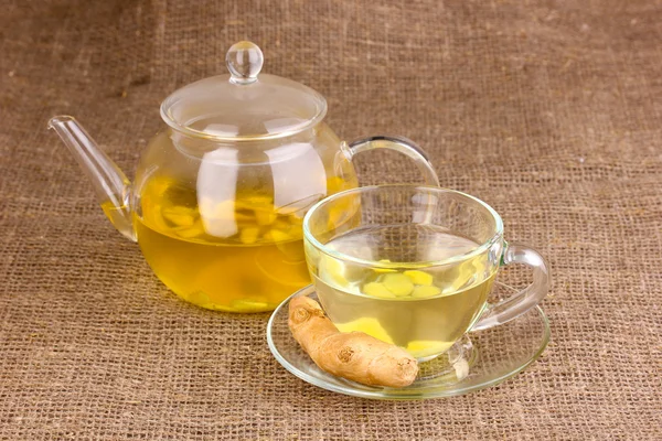 Healthy ginger tea in kettle and cup on sackcloth — Stock Photo, Image
