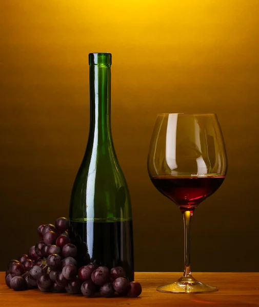 Composition of wine bottle and wineglass on wooden table on brown background — Stock Photo, Image