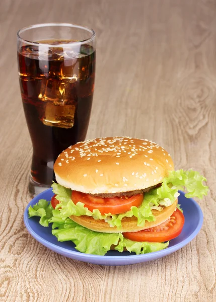 Grote en smakelijke hamburger op plaat met cola op houten tafel — Stockfoto