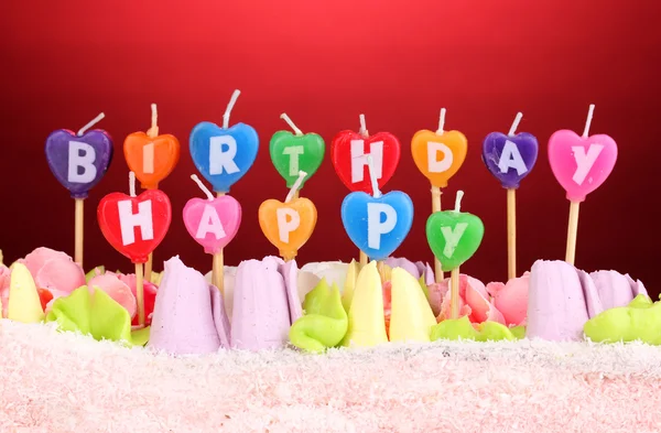 Verjaardagscake met kaarsen op rode achtergrond — Stockfoto