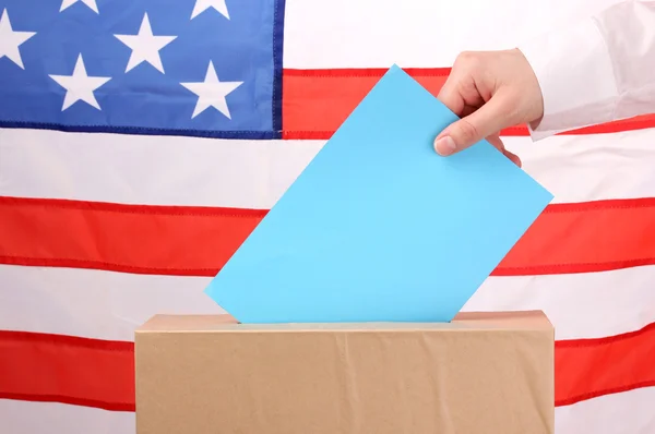 Mano con voto e scatola sulla Bandiera degli Stati Uniti — Foto Stock