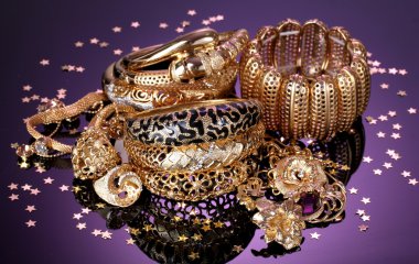 Beautiful golden jewelry on purple background clipart