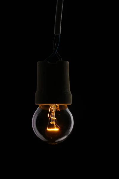 En tänd glödlampa på svart bakgrund — Stockfoto