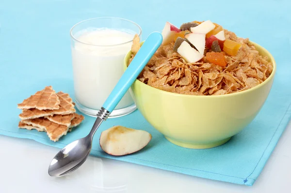 Leckere Cornflakes in Schüssel mit getrockneten Früchten und einem Glas Milch auf blauer Serviette — Stockfoto