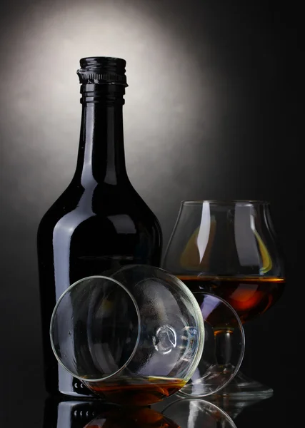 Gläser Schnaps und Flasche auf grauem Hintergrund — Stockfoto