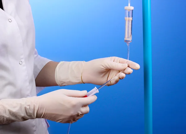 Enfermera haciendo infusión sobre fondo azul —  Fotos de Stock