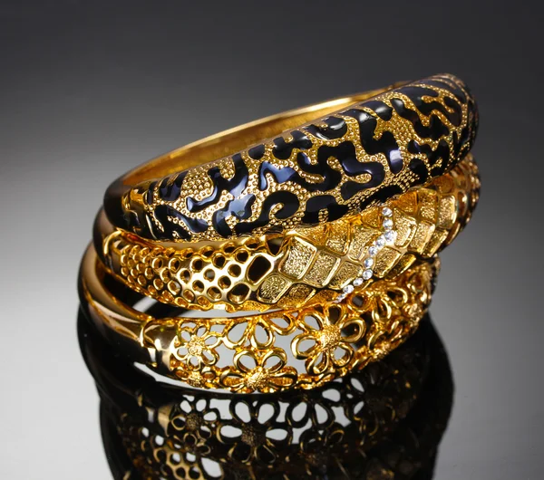 Beaux bracelets dorés sur fond gris — Photo