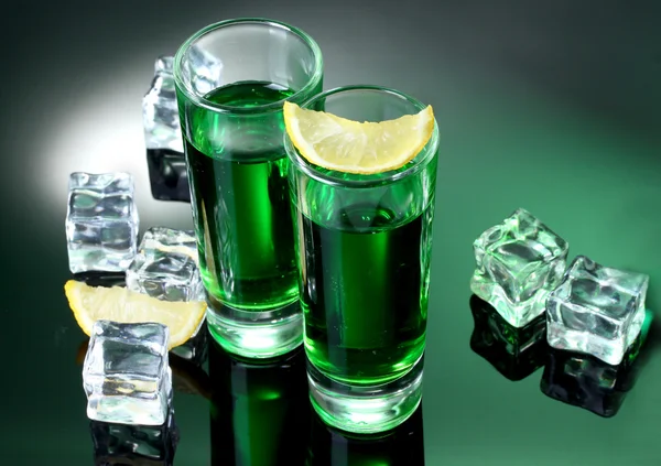 Zwei Gläser Absinth, Zitrone und Eis auf grünem Hintergrund — Stockfoto