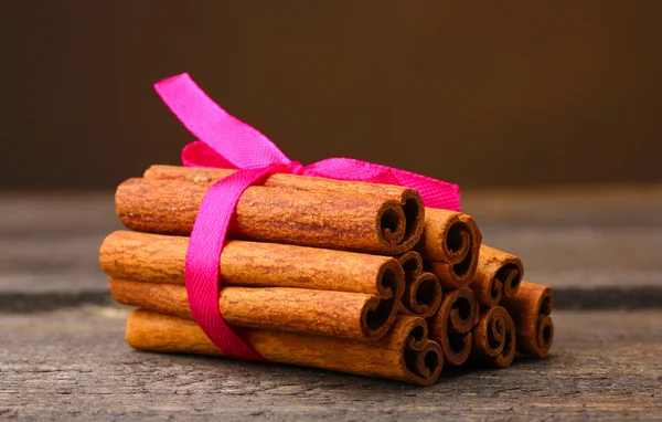 Cinnamon sticks on wooden table on brown background — Stock Photo, Image