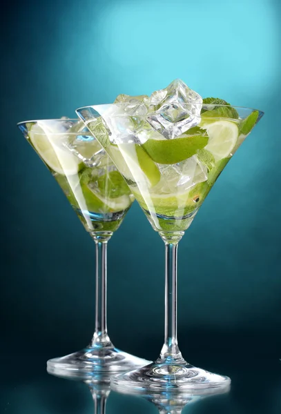 Glazen van cocktails met limoen en munt op blauwe achtergrond — Stockfoto