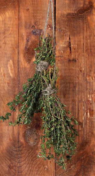 Tomilho verde fresco pendurado na corda no fundo de madeira — Fotografia de Stock