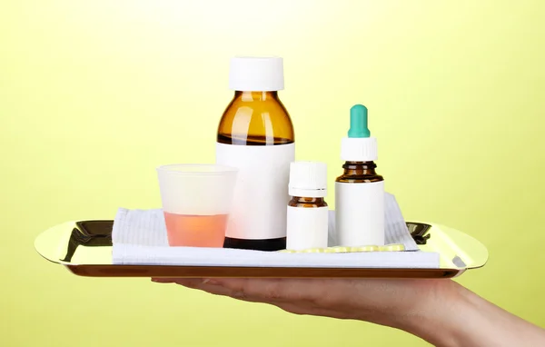 Håndholder bakke med medicin på grøn baggrund - Stock-foto