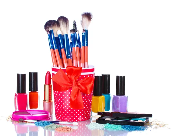 Cepillos de maquillaje en taza y cosméticos aislados en blanco —  Fotos de Stock