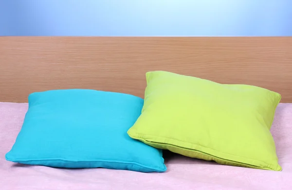 Φωτεινό μαξιλάρια στο κρεβάτι σε μπλε φόντο — Φωτογραφία Αρχείου