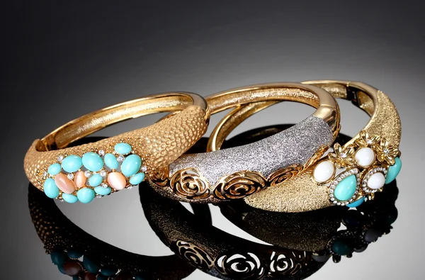 Belas pulseiras douradas no fundo cinza — Fotografia de Stock