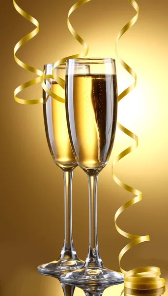 Copos de champanhe e streamer no fundo amarelo — Fotografia de Stock