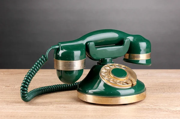 Ретро-телефон на деревянном столе на сером фоне — стоковое фото