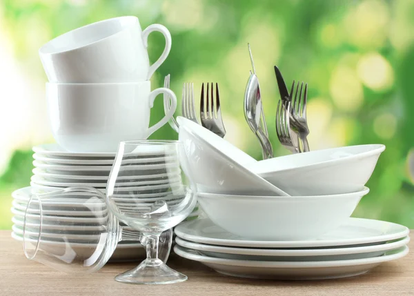 Platos limpios sobre mesa de madera sobre fondo verde — Foto de Stock