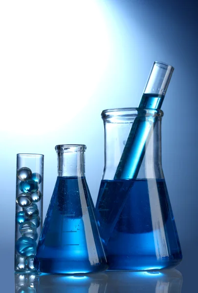 Tubos de ensaio com líquido azul sobre fundo azul — Fotografia de Stock