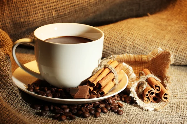 Tazza di caffè e fagioli, bastoncini di cannella e cioccolato sul fondo del sacco — Foto Stock