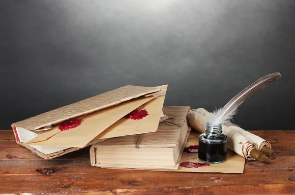 Régi könyvek, tekercsek, toll, toll és a fából készült asztal-szürke háttér inkwell — Stock Fotó