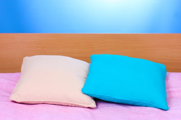 Bright pillows on bed on blue background — Stock Photo, Image