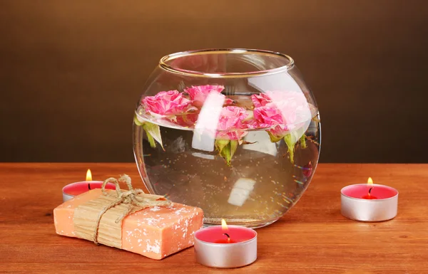 Спа композиция свечей, мыла и розовых роз, плавающих на деревянном фоне — стоковое фото