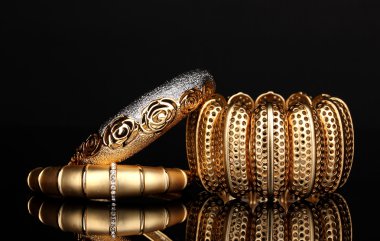 Beautiful golden bracelets isolated on black background clipart