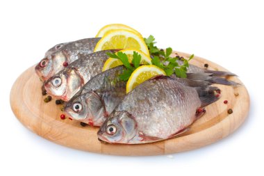 limon, maydanoz ve baharat üzerine beyaz izole ahşap kesme tahtası üzerinde taze balıklar