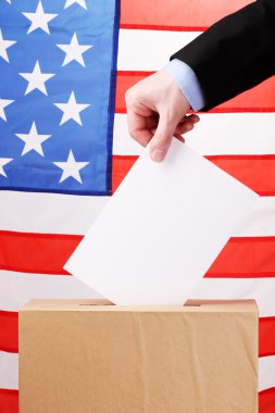 Hand with voting ballot and box on Flag of USA clipart