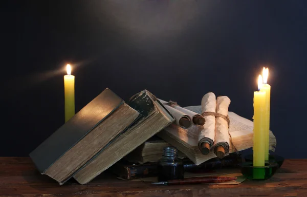Vecchi libri, pergamene, calamaio penna piuma e candele su tavolo di legno su sfondo blu — Foto Stock
