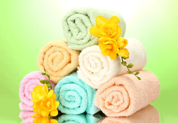 Kleurrijke handdoeken en bloemen op groene gele achtergrond — Stockfoto