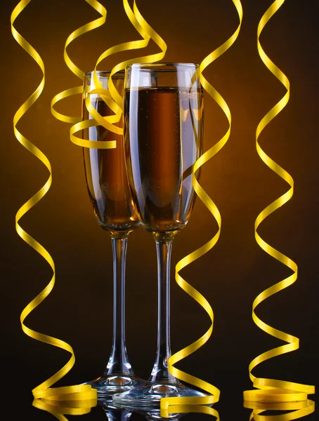 Glasses of champagne and streamer on brown background — Stock Photo, Image