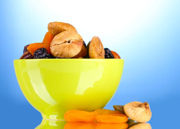 Dried fruits in green bowl on blue background — Stock Photo, Image