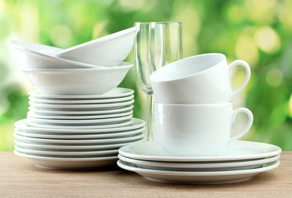 Čisté nádobí na dřevěný stůl na zeleném pozadí — Stock fotografie