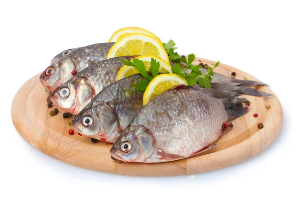 新鲜鱼类与柠檬、 香菜和香料在木菜板上白色隔离 — 图库照片