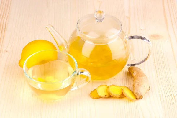 Healthy ginger tea in kettle and cup with lemon on wooden background — Stock Photo, Image