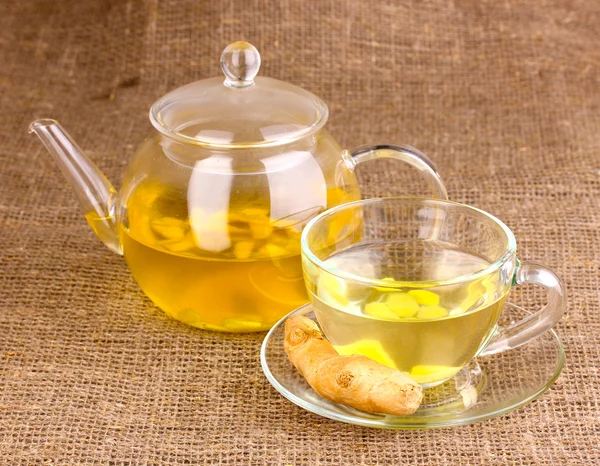 Healthy ginger tea in kettle and cup on sackcloth — Stock Photo, Image