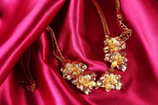 Vackra guld halsband på röda sidentyg — Stockfoto