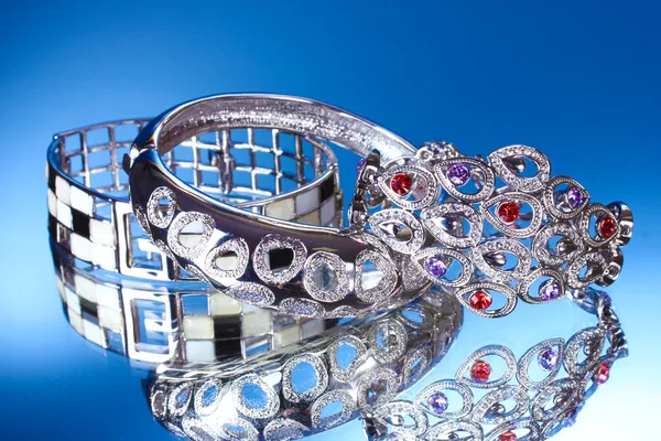 Красивые серебряные браслеты на синем фоне — стоковое фото