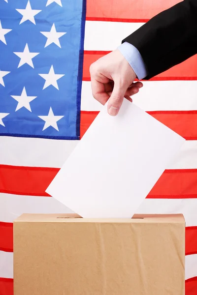Mano con papeleta de votación y caja en Bandera de Estados Unidos —  Fotos de Stock
