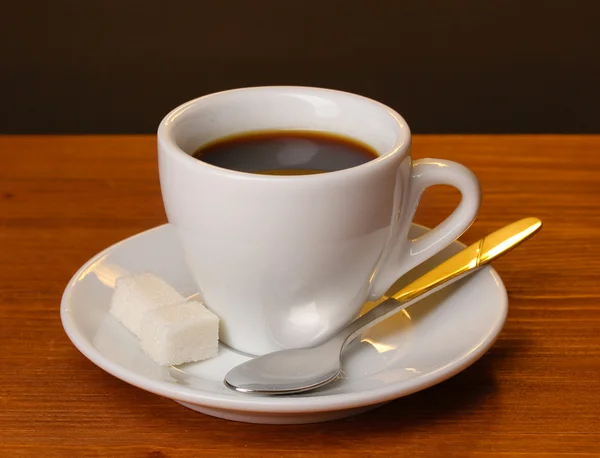 Šálek kávy na dřevěný stůl na hnědé pozadí — Stock fotografie