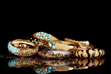 Beautiful golden bracelets isolated on black background clipart