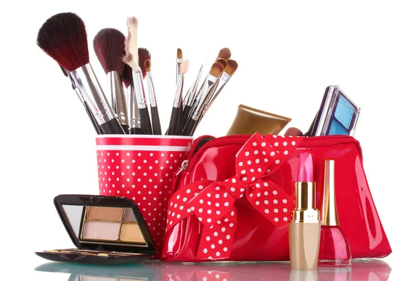 Vidro vermelho com escovas e saco de maquiagem com cosméticos isolados em branco — Fotografia de Stock